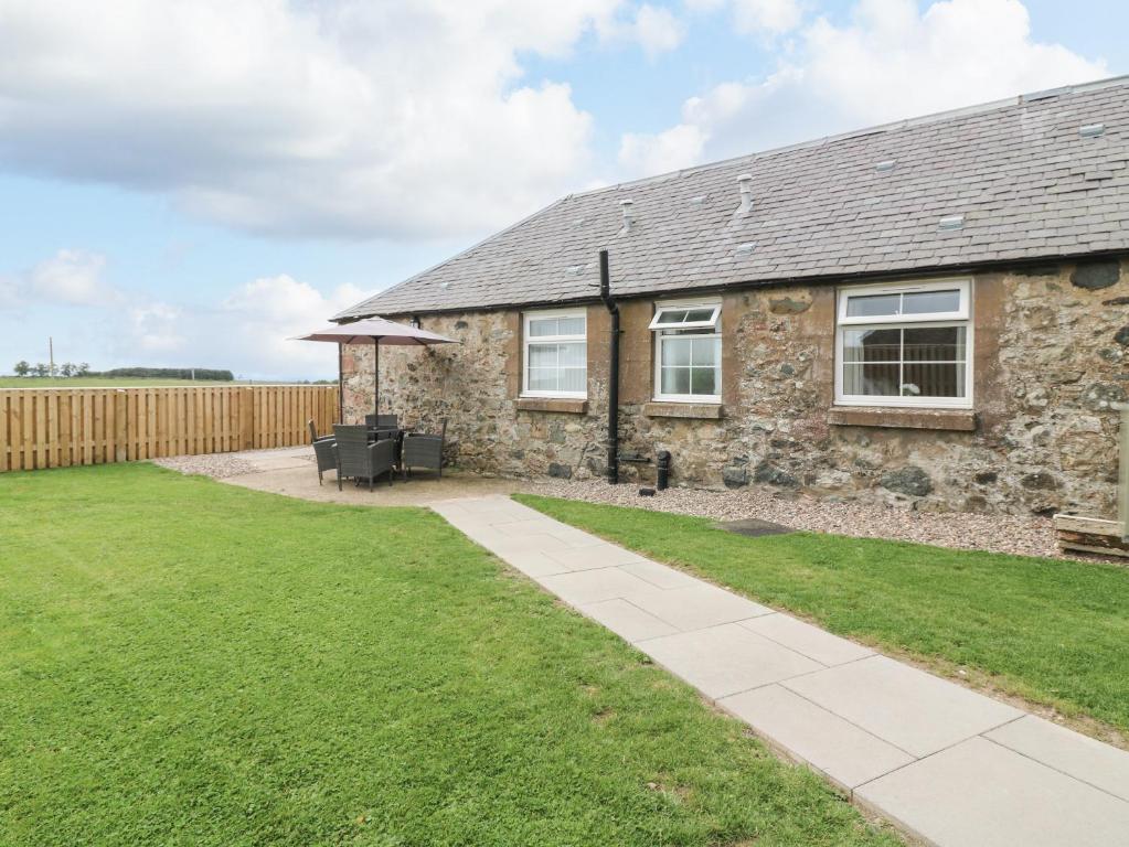 ein Steinhaus mit Rasen davor in der Unterkunft Sportsmans Lodge in Kirriemuir