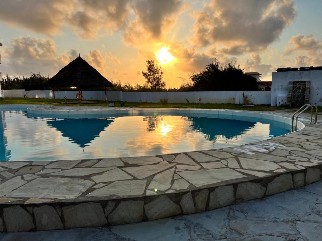 a swimming pool with a sunset in the background at Kijani Paradise Malindi in Malindi