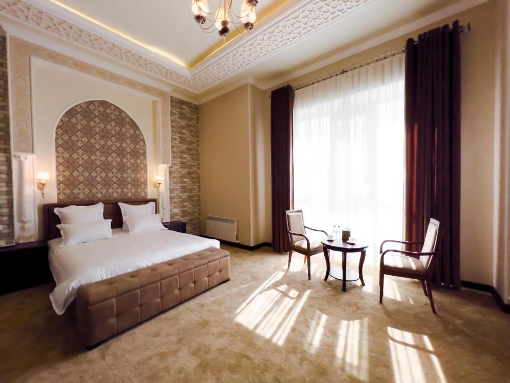 um quarto com uma cama, uma mesa e uma janela em Marakanda Hotel Samarkand em Samarkand