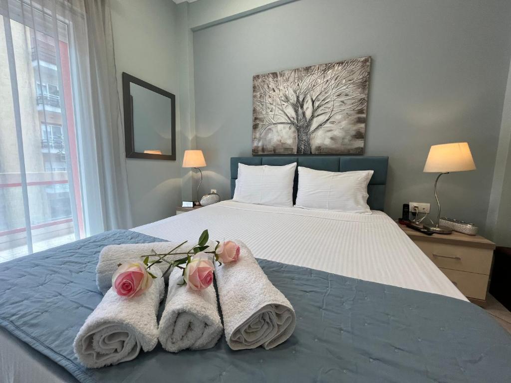 a bedroom with a bed with towels and flowers on it at Kavala Port Apartments in Kavála