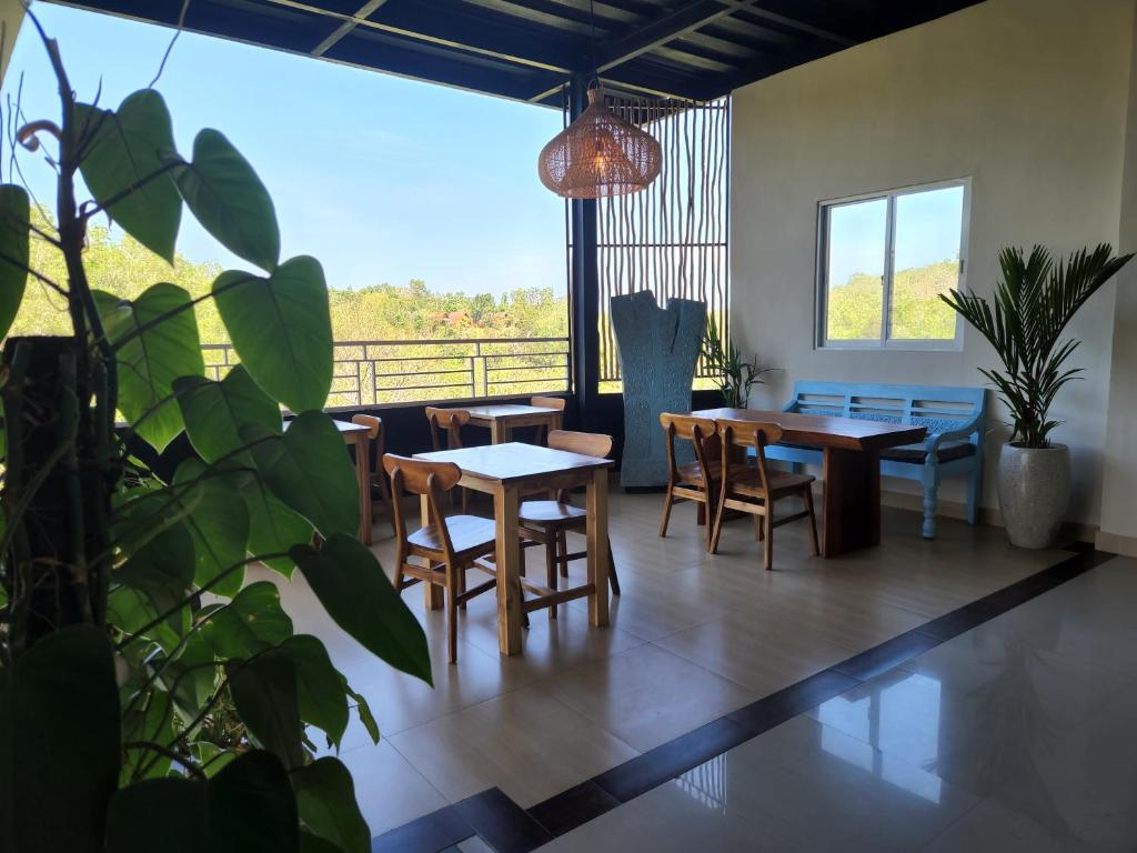uma sala de jantar com mesas e cadeiras e uma grande janela em Bagus Ink Surf Camp em Uluwatu