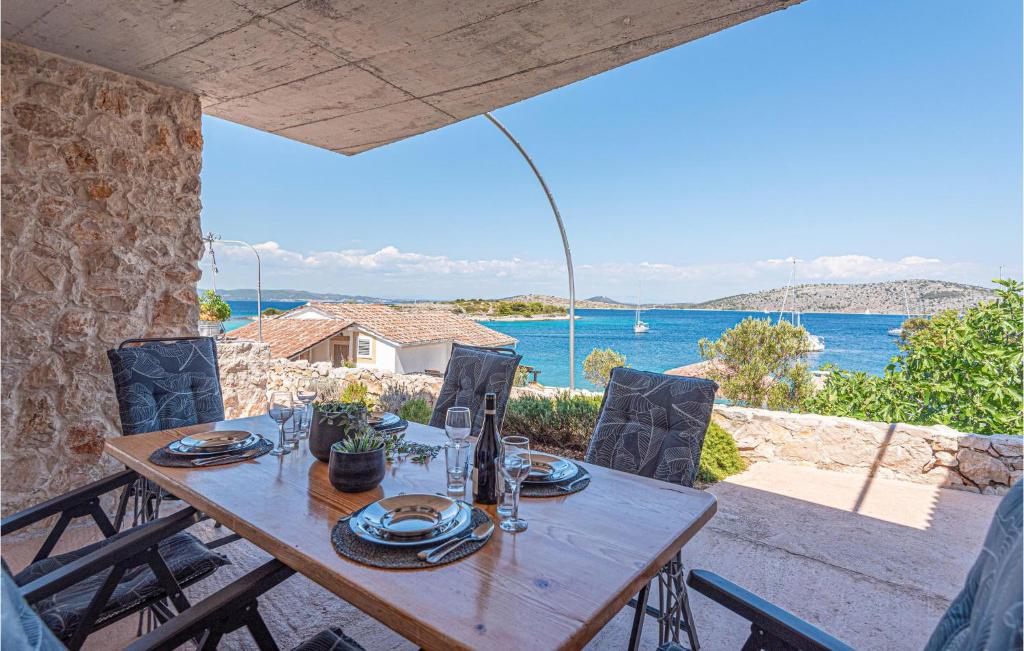 een houten tafel met stoelen en uitzicht op de oceaan bij Nice Home In Sibenik With Wifi And 2 Bedrooms in Šibenik