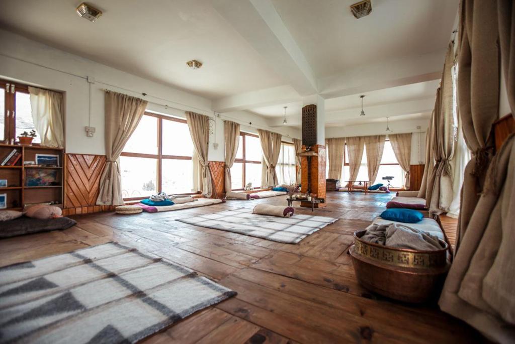 Panorama Inn Mustang في Muktināth: غرفة معيشة كبيرة مع أرضيات خشبية ونوافذ كبيرة