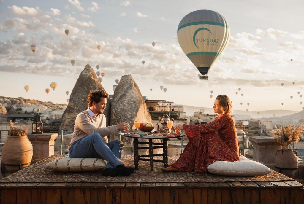 a man and woman sitting at a table with a hot air balloon at Sultan Cave Suites in Göreme