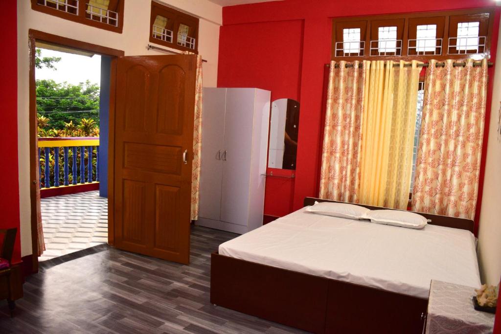 Schlafzimmer mit einem Bett, einem Kühlschrank und einer Tür in der Unterkunft J&B Homestay in Dibrugarh