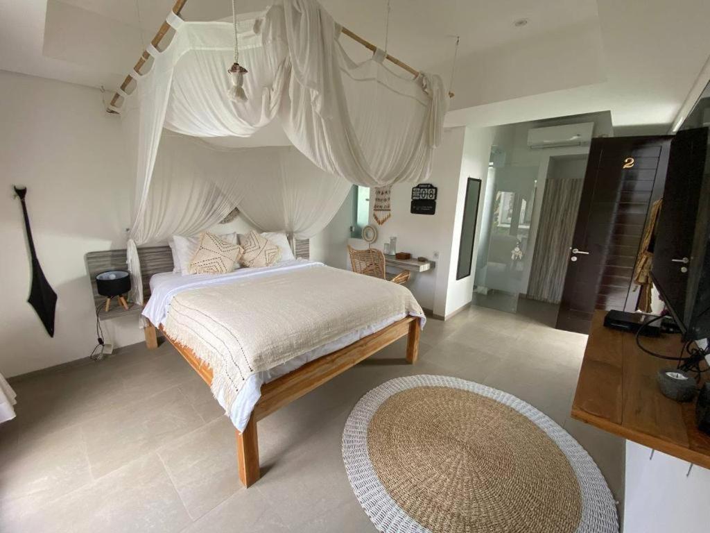 a bedroom with a bed with a canopy and a rug at Villa Kalma Canggu in Canggu