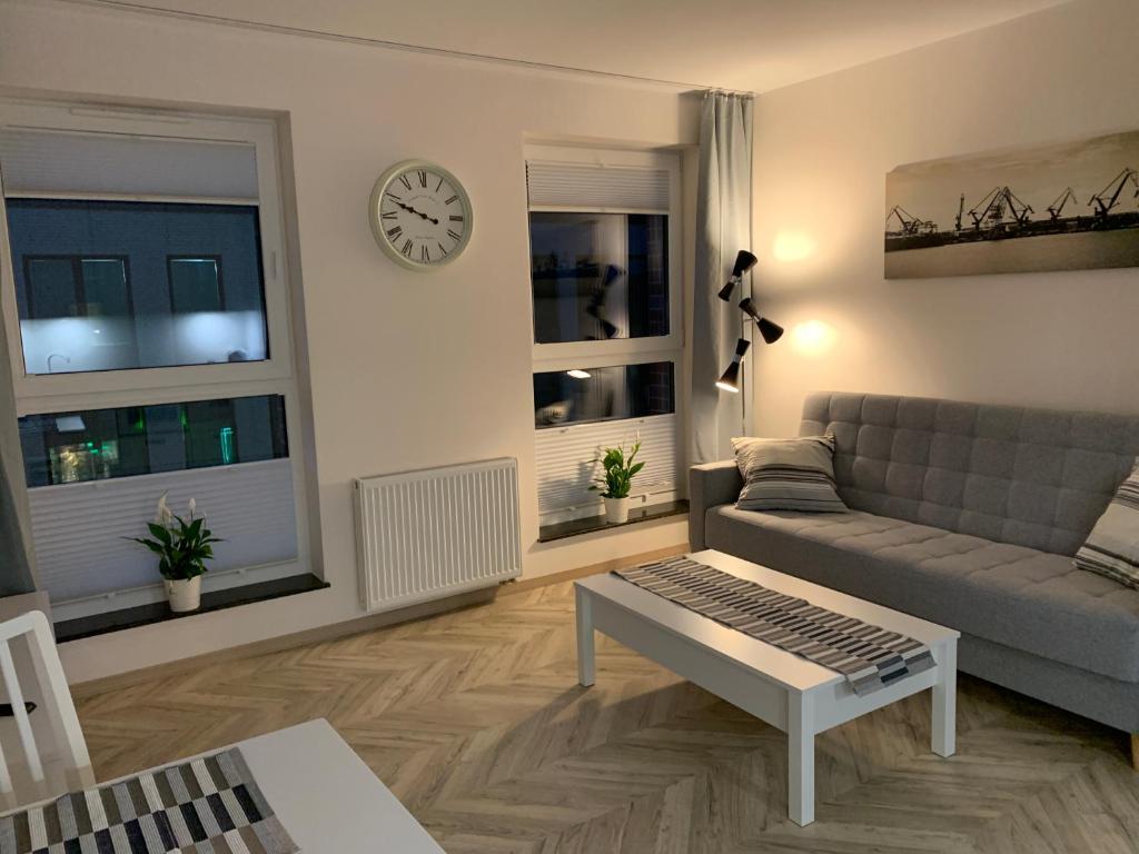 a living room with a couch and a clock on the wall at Olin Apartament B - Gdańsk Angielska Grobla in Gdańsk