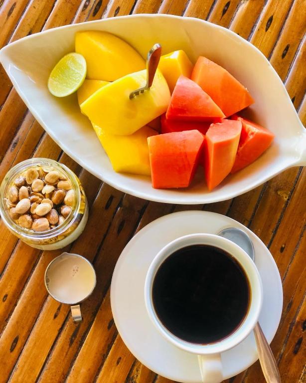 a plate of fruit and a cup of coffee on a table at Bambu Huts in Baan Tai