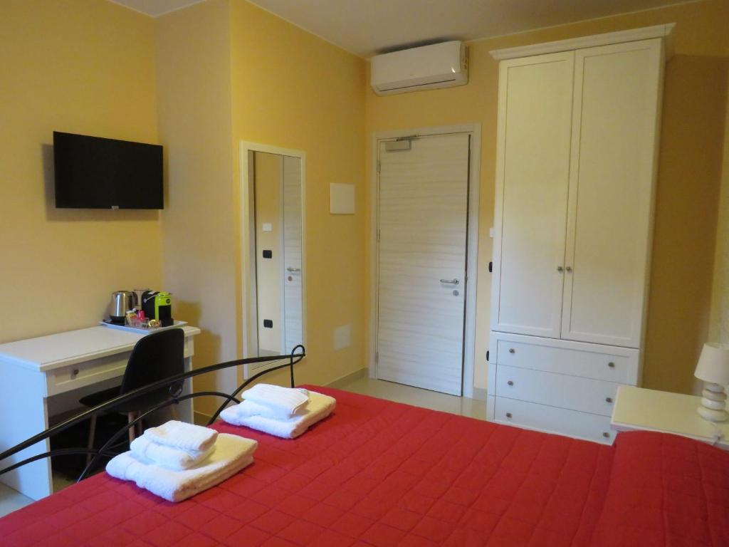 een slaapkamer met een rood bed en handdoeken erop bij B&B Romano in Gela