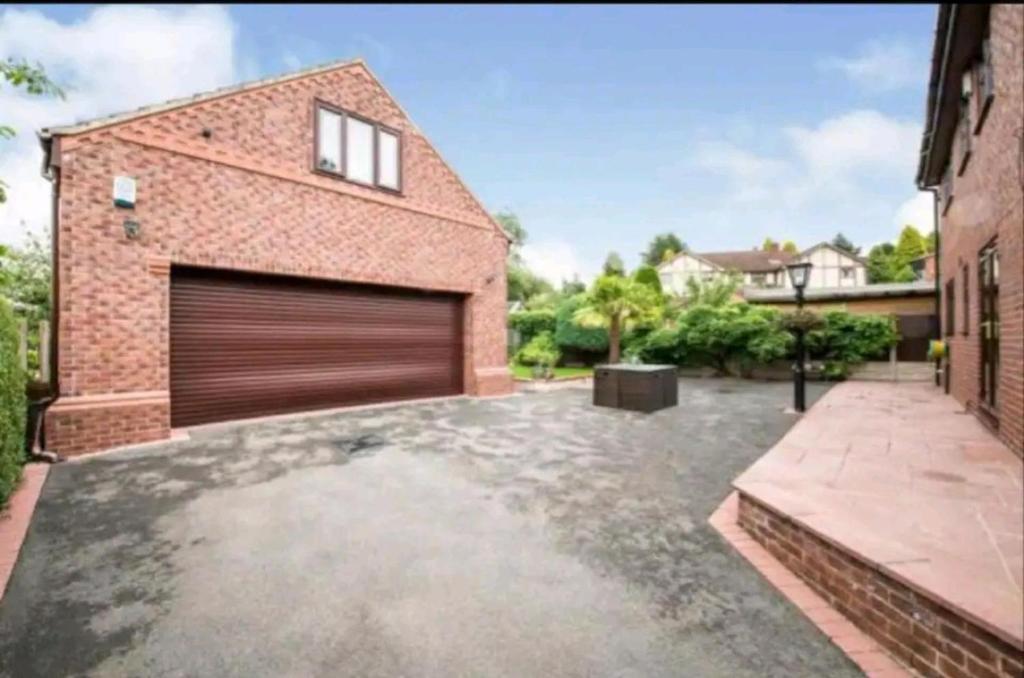 a brick building with a garage door in a driveway at 1 Bedroom Annexe Bagthorpe Brook Nottinghamshire in Nottingham