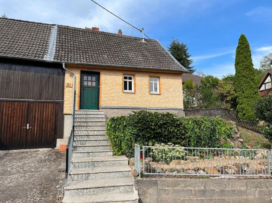 une maison en briques avec une porte verte et des escaliers dans l'établissement Landhaus inklusive Parkplatz, à Schotten