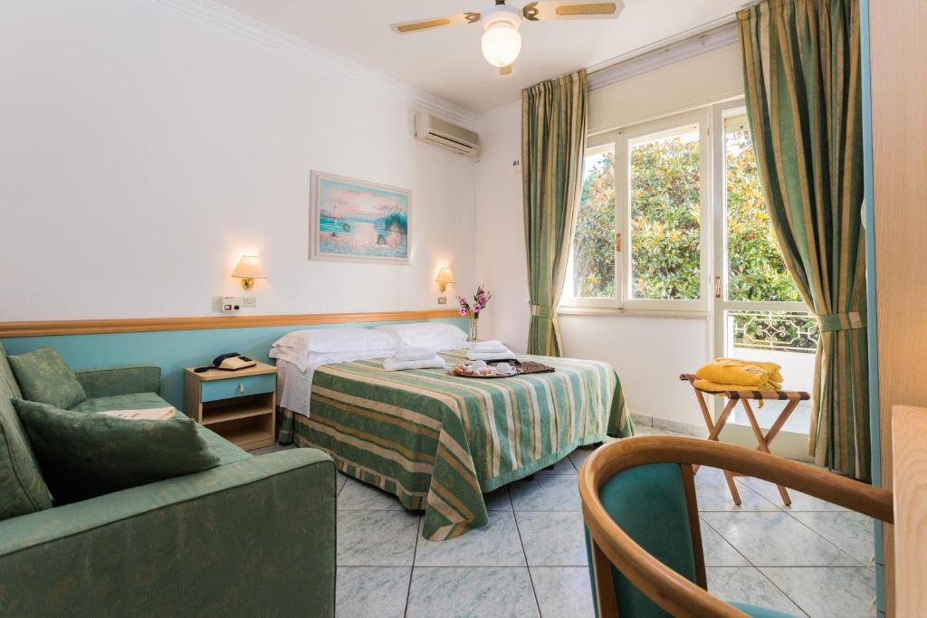 una camera d'albergo con letto, divano e finestra di Hotel Bamby a Cervia