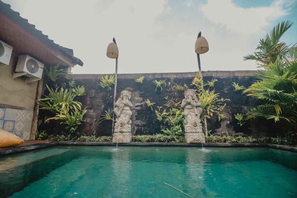 a swimming pool with statues in front of a house at Samblung Mas House in Denpasar