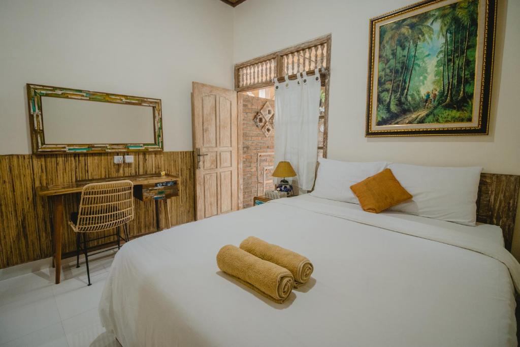 una camera da letto con un grande letto bianco e uno specchio di Samblung Mas House a Denpasar