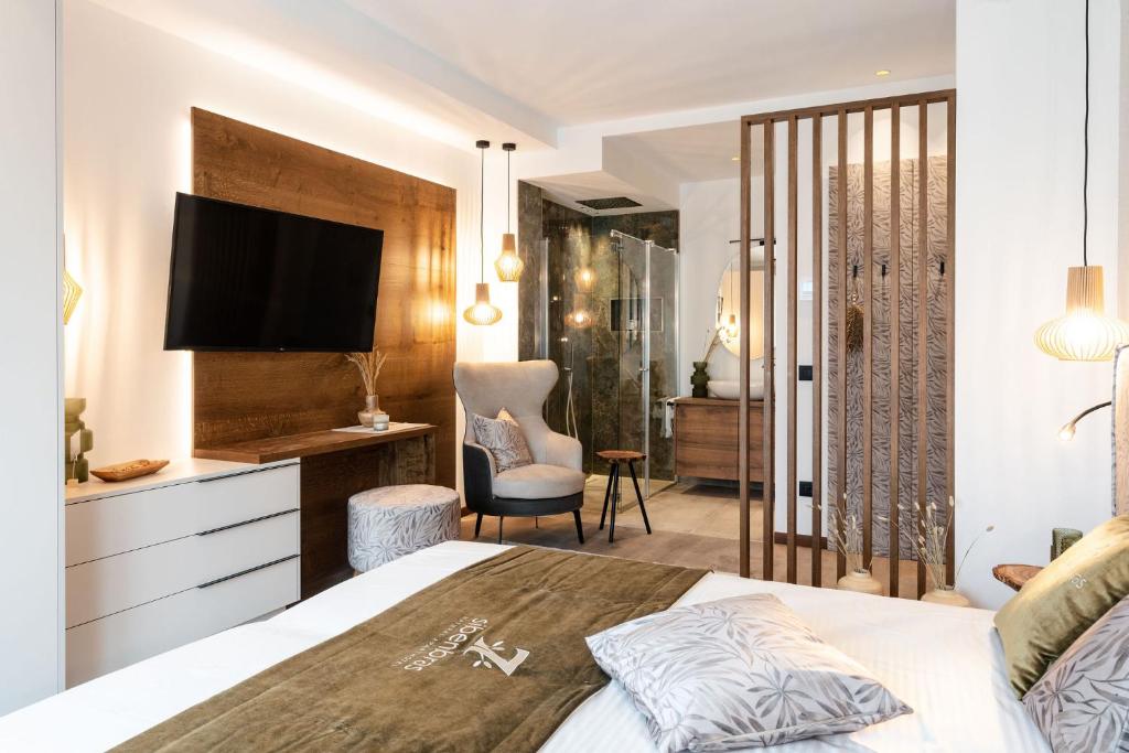 1 dormitorio con 1 cama, TV y escritorio en Sibenbras Natural Aparthotel, en Limone sul Garda