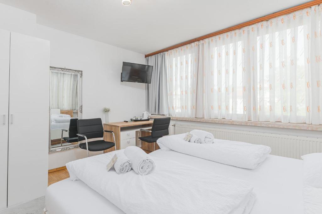 a bedroom with two beds and a desk with chairs at Hotel am Schlossplatz in Hechingen