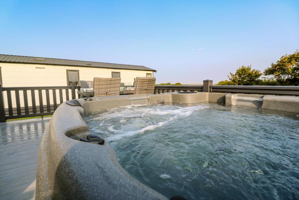 a hot tub on a patio with two chairs at Chantry Lodge in Newquay