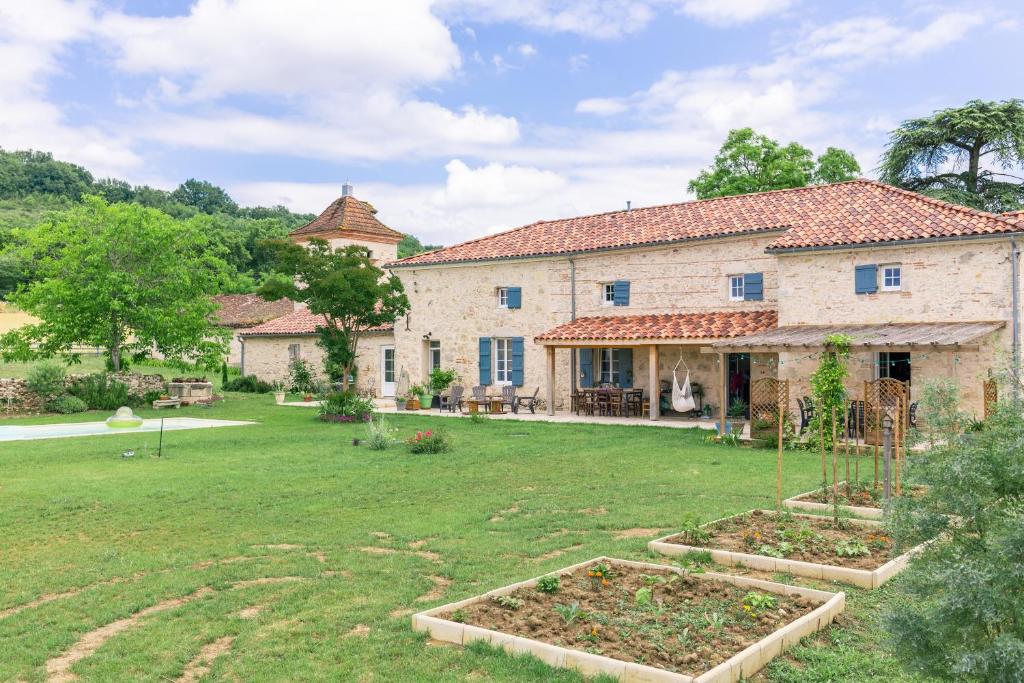 duży kamienny dom z ogrodem na dziedzińcu w obiekcie Le Clos Saint-Jean - Chambre d'hôte Rosie w mieście Saint-Jean-de-Thurac