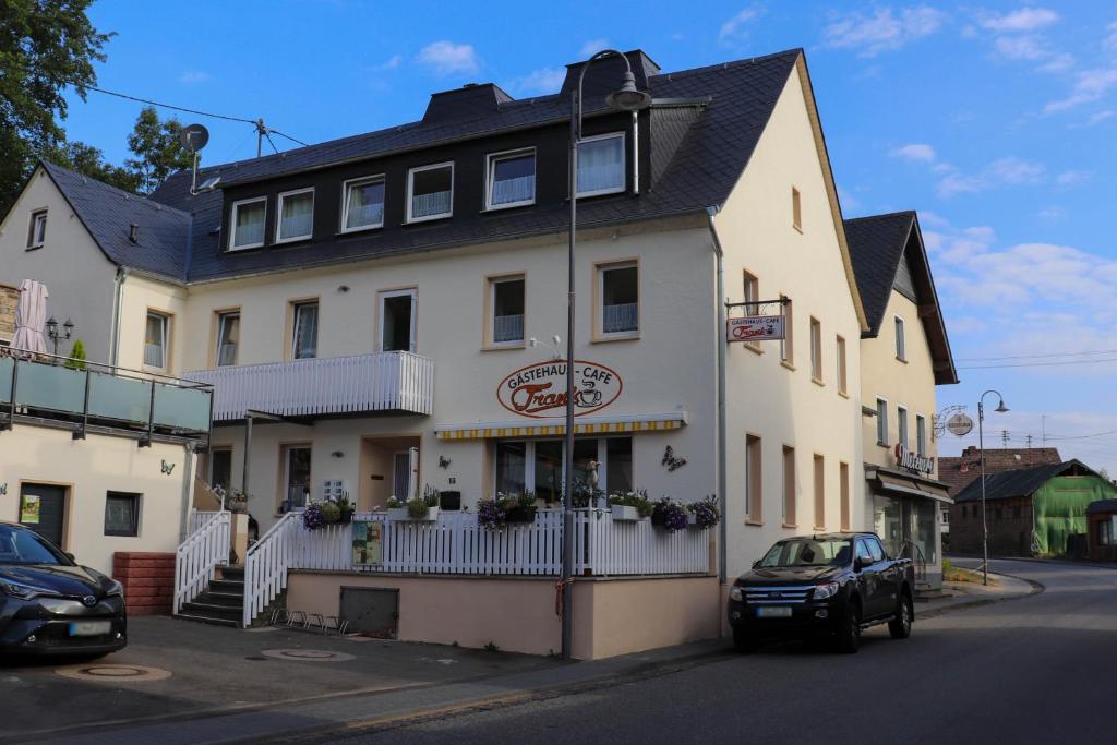 ein weißes Gebäude mit einem davor geparkt in der Unterkunft Gästehaus - Café Frank in Antweiler