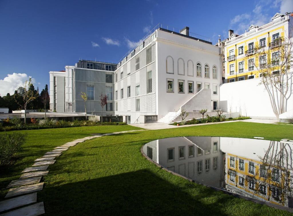 un grand bâtiment blanc avec une réflexion sur l'herbe dans l'établissement Hotel da Estrela - by Unlock Hotels, à Lisbonne