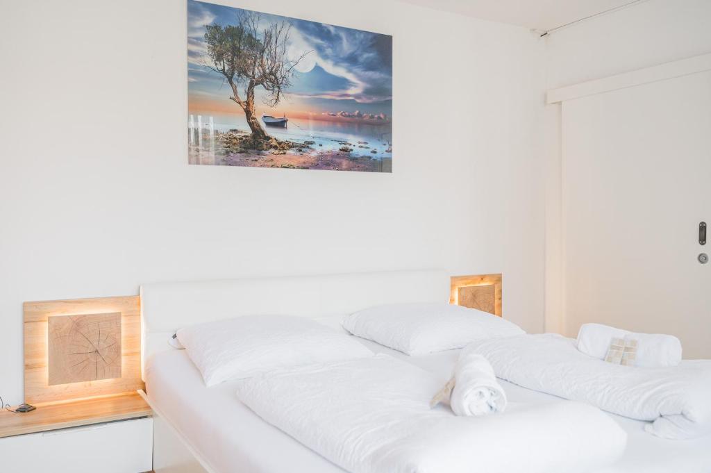 Una cama blanca en una habitación con una foto en la pared en Hotel am Schlossplatz en Hechingen