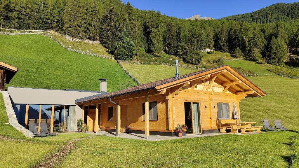 una cabaña de madera en una colina con un campo verde en Ferienhütte Premstlahof - Chalet, en Martello