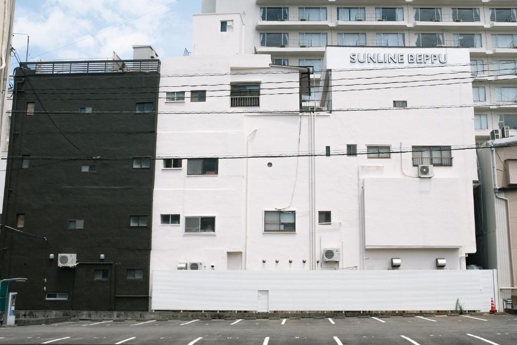 別府市にあるゲストハウスサンライン別府の日焼け剤の看板が付いた白い建物