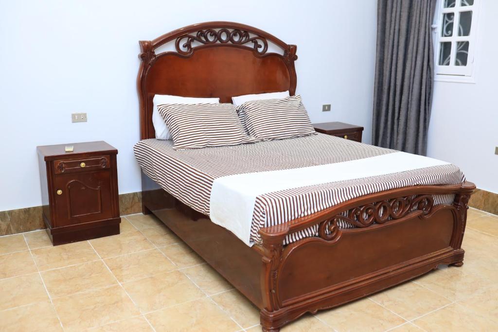 1 dormitorio con cama con marco de madera y almohadas en Full Moon House en Luxor