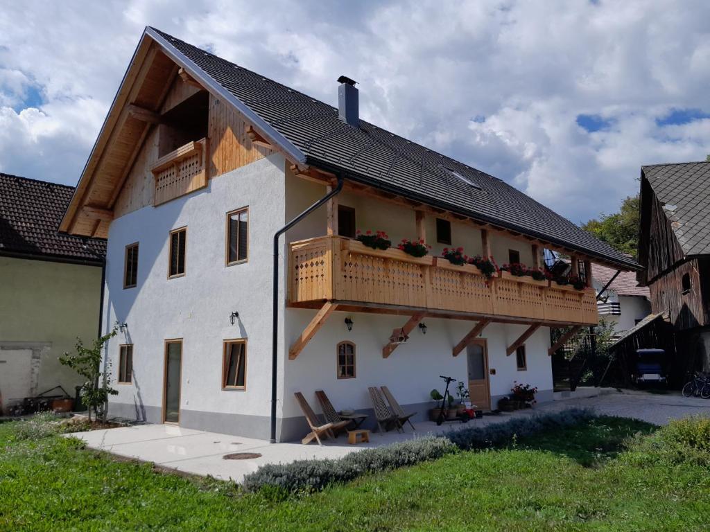 een wit huis met een balkon en 2 stoelen bij Turistična kmetija Grabnar in Bled