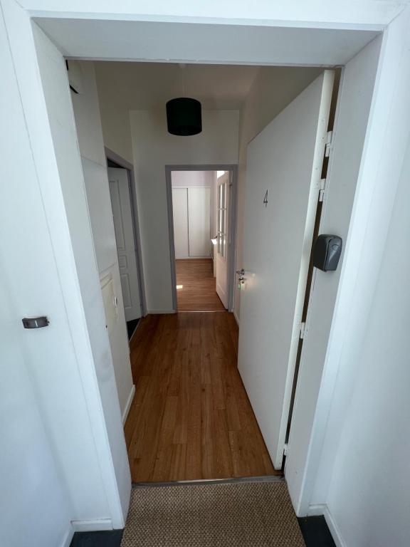 um corredor de um apartamento com paredes brancas e pisos de madeira em Charmant appartement RDC familial ou pour le travail em Uzerche
