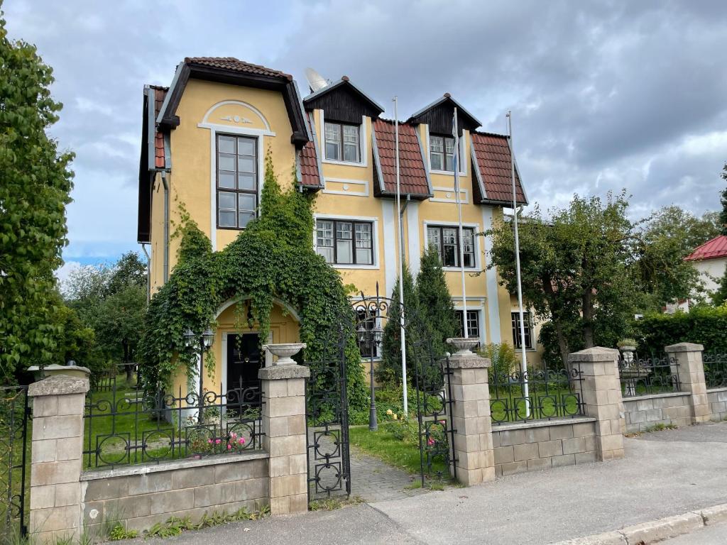 a large yellow house with an ivy covered fence at Vikerkaare Villa in Tartu