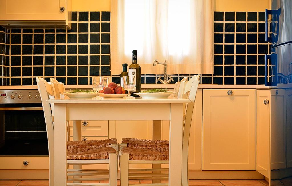 una cucina con tavolo bianco con sedie e una bottiglia di vino di Olive Coast Suites a Paleocastro (Palekastron)