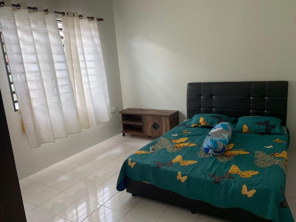 een slaapkamer met een bed met een groen dekbed bij Homestay Maryam in Lumut