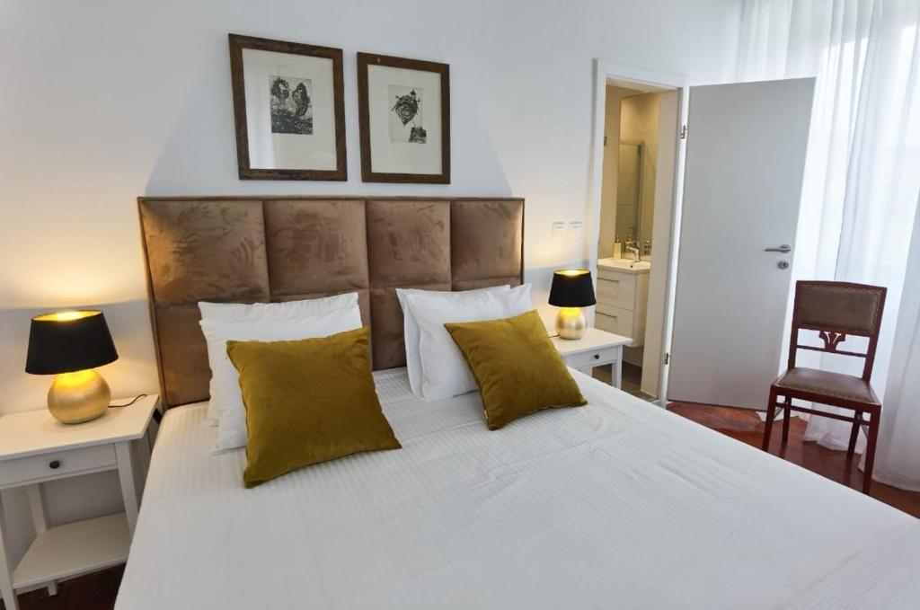 um quarto com uma grande cama branca com almofadas amarelas em Apartment Emma em Preko