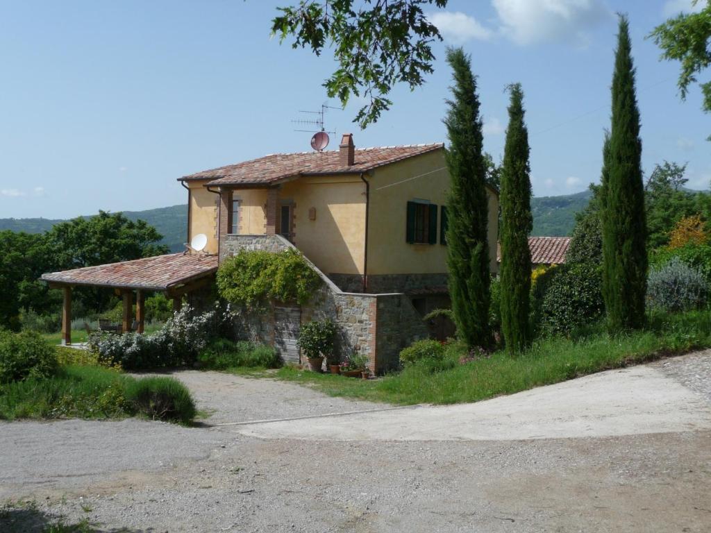 una casa en un campo con árboles y una carretera en Podere Sant'Angelo en Roccalbegna