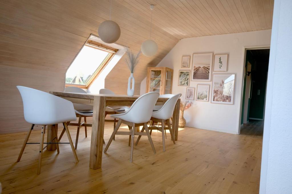 een eetkamer met een tafel en witte stoelen bij Frühlingsbogen in Harrislee