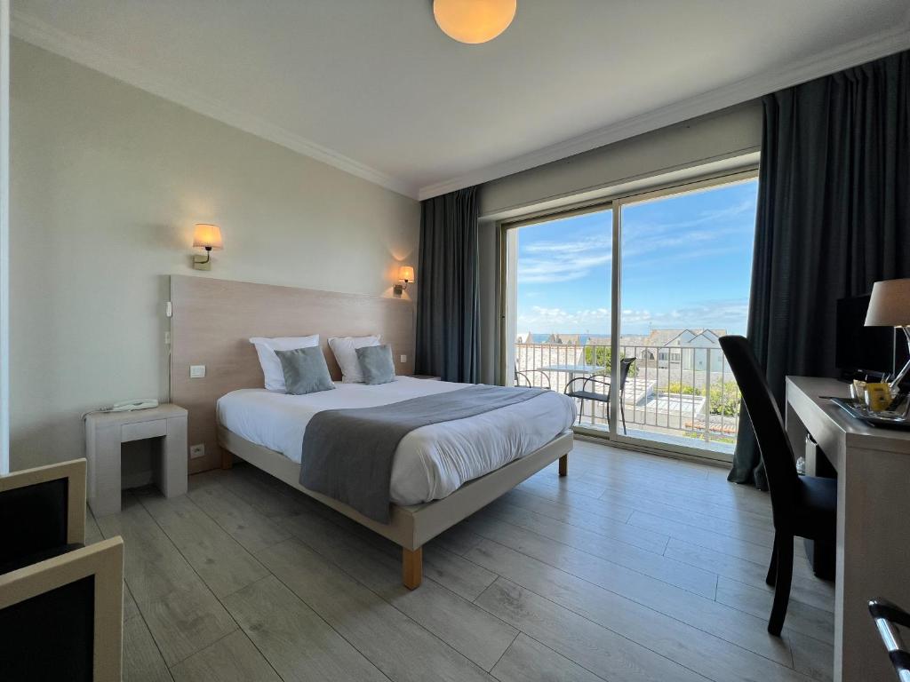 a hotel room with a bed and a large window at Hôtel Ker-Noyal Quiberon Plage in Quiberon
