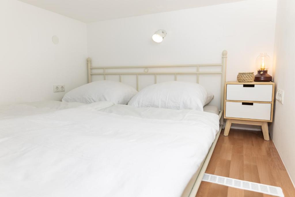 1 dormitorio con 2 camas blancas y mesita de noche en Cozy studio, private garden, 8 min to city center en Viena