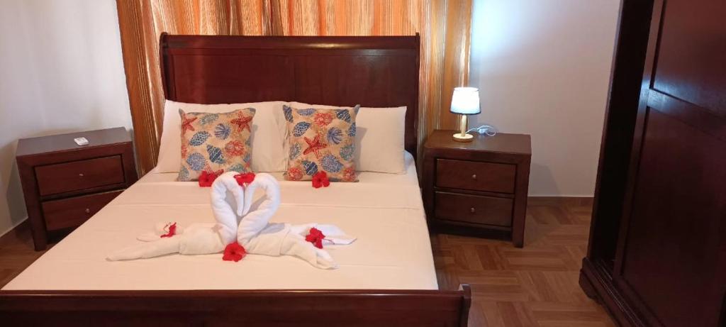 - une chambre avec 2 lits avec des draps blancs et des archets rouges dans l'établissement Sawa self catering, à Pointe Au Sel 