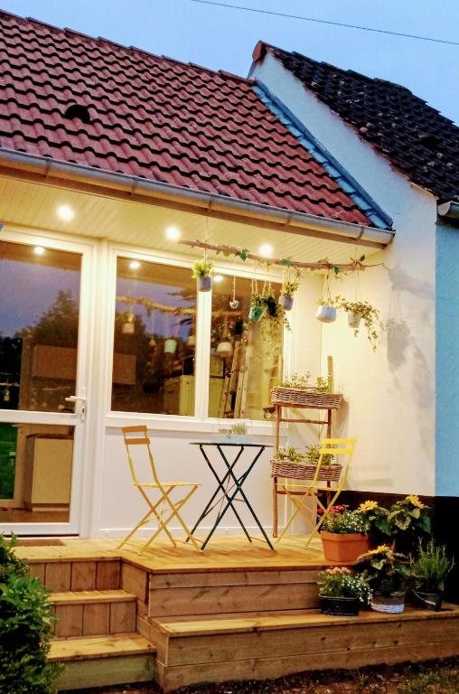 une maison dotée d'une terrasse couverte avec 2 chaises. dans l'établissement Le cottage du Marais., à Houlle