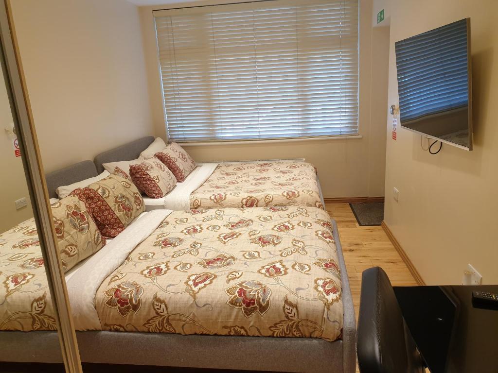 a bedroom with two beds and a television in it at London Luxury Apartments 1 min from Redbridge Station with Parking in Wanstead