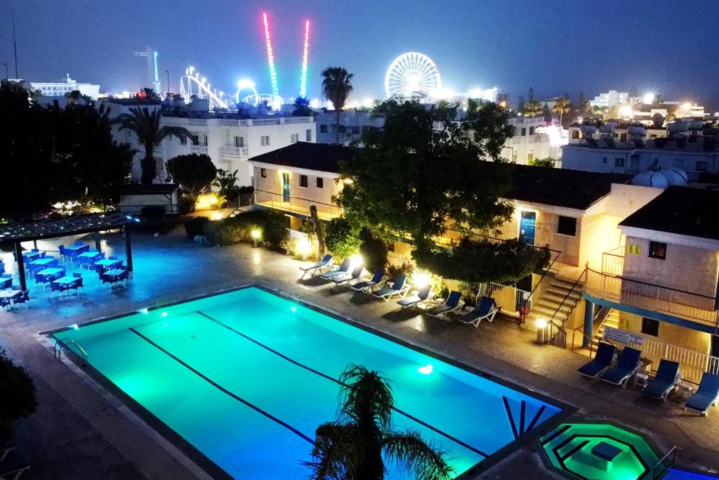a swimming pool at night with a ferris wheel in the background at Green Bungalows Hotel Apartments in Ayia Napa
