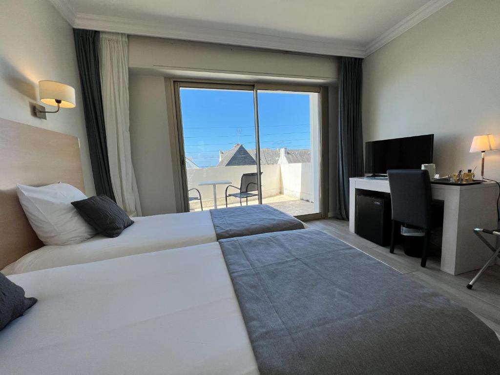 a hotel room with two beds and a desk and a window at Hôtel Ker-Noyal Quiberon Plage in Quiberon