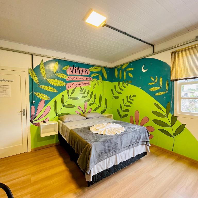 a bedroom with a bed with a mural on the wall at Araucária Hostel e Pousada in São Bento do Sul