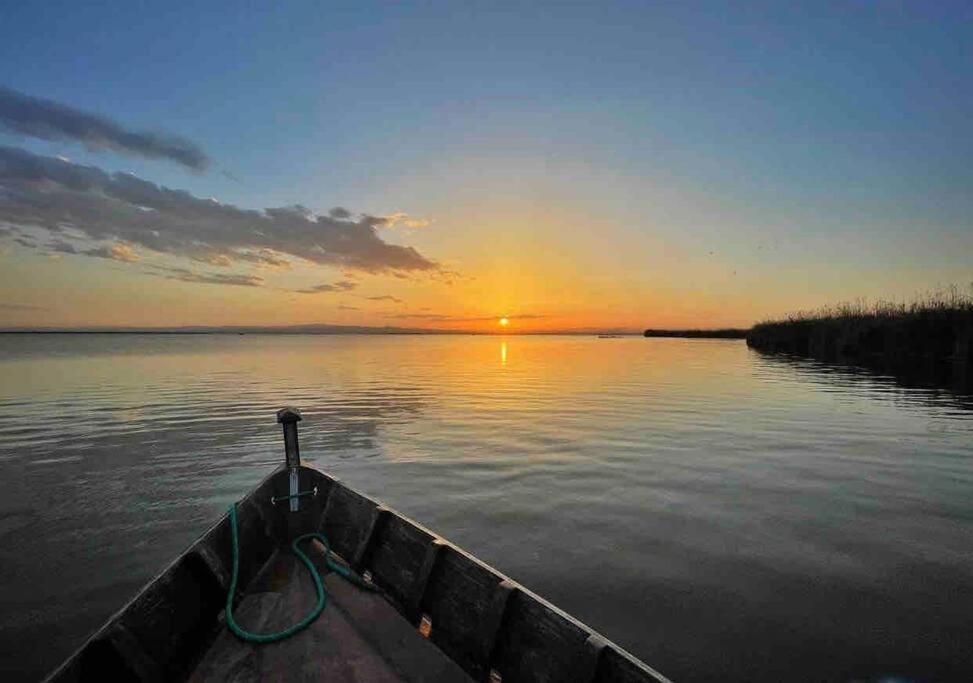 a boat on a lake with the sun setting at Agradable adosado con zona de aparcamiento in Sedaví