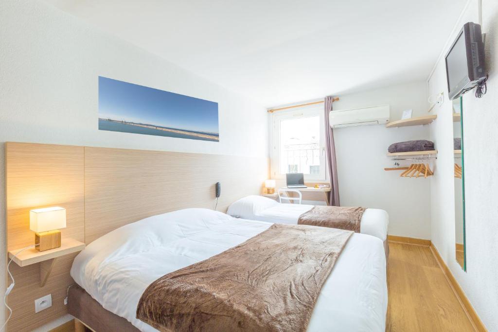 a bedroom with two beds and a television in it at Europe Hotel Vieux Port in Marseille
