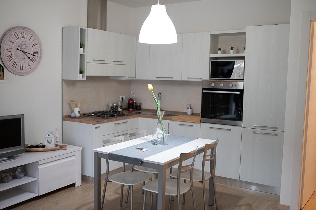 une cuisine blanche avec une table, des chaises et une horloge dans l'établissement La casa di Anna, à Domegliara