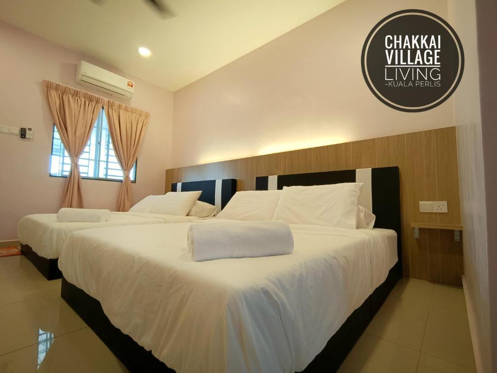 Chakkai Village Living Guest House في كوالا برليس: سريرين في غرفة الفندق ذات شراشف بيضاء