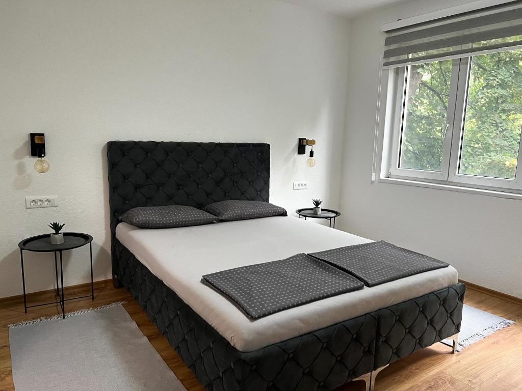 een slaapkamer met een groot bed met een zwart hoofdeinde bij Apartment Vils Promenade in Sarajevo