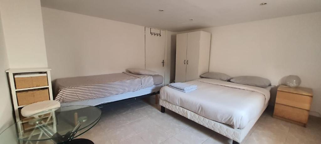 a small room with two beds and a glass table at Charmant appartement 2p avec piscine partagée in La Ferté-Gaucher